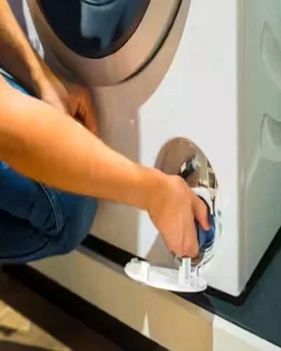 Technician accessing a washing machine base panel to fix noise and vibration